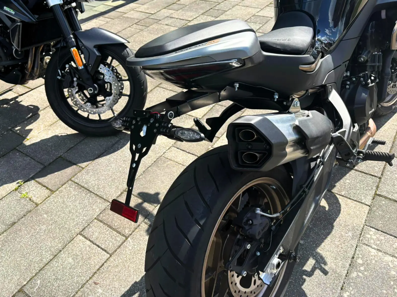 Detailaufnahme des Hecks der CFMOTO 800NK mit Auspuffanlage, Hinterrad und Kennzeichenhalter